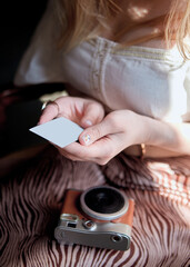 Close view of a girl holding a photo card from a retro camera mockup