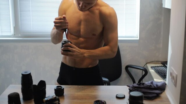 bare-chested man cleans and cares for optics and camera lenses.