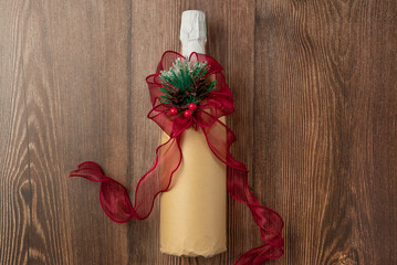 Wrapped champagne bottle with ribbon on wooden background. Top view