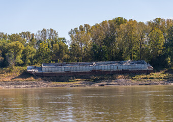 Low water on the Mississippi river beaches a moored barge on the river bank or levee by the side of...