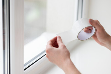 Man putting draught excluder tape on window, protection from the draft.