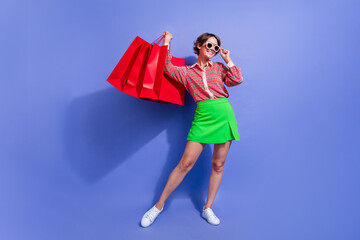Full size photo of gorgeous woman dressed print shirt hold outfit in bags touching sunglass buy...