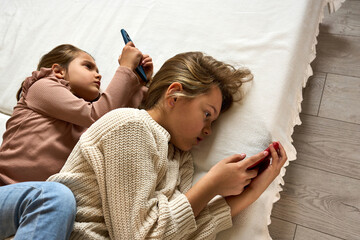 Two little girls/sissters on a bed, captivated by screens instead of play. A poignant look at how...