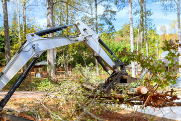 Skid steer tractor aids in tree clearing for housing complex construction during landscaping © ungvar
