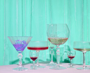 Elegant cocktail glasses, aquamarine velvet curtain background, creative, aesthetic party layout.