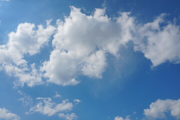 White fluffy clouds in the sky. Blue sky and cloud cover on a sunny summer day. Empty background, copy space