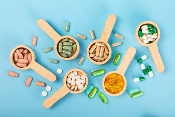 Vitamins and supplements. Variety of vitamin tablets in wooden spoons on a texture background. Multivitamin complex for every day. Nutritional supplements. Place for text. Copy space.