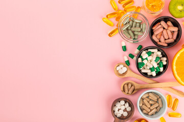 Vitamins and supplements. Variety of vitamin tablets in bowls on a pink background. Multivitamin...