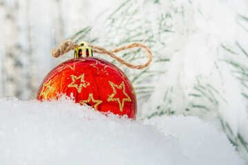 A red ball with stars drowned in a snowdrift in a winter forest. The concept of Christmas