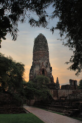 Buddhist stupa in Ayutthaya during sunset with frame of trees in the foreground