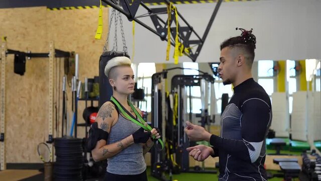 Male personal trainer giving consultation to client during the training in gym.