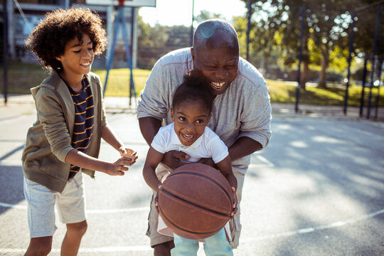 Joyful Family Playing Basketball Together on Sunny Day