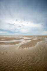 sand, low tide with ripples and reflections.