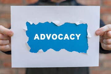 Man holding white and blue sheets of paper with word: ADVOCACY. Business advocacy and lawyer...