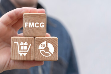 Man holding wooden blocks with icon sees abbreviation: FMCG. FMCG or Fast Moving Consumer Goods...