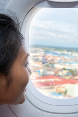 A young woman looks out of the window in a flying plane