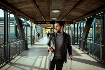 Young bearded businessman checking smartphone at train station