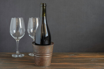 Bottle of red wine on the background of wine glasses and dark wooden background.