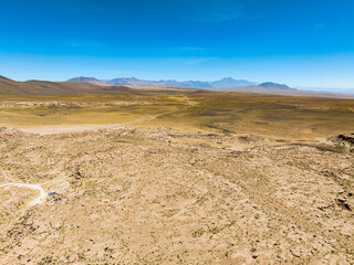 Região desértica ao lado do vilarejo de Socaire no Chile. Areia, dunas, céu azul e paisagem árida.