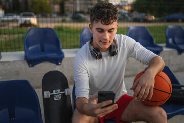 caucasian teen using mobile phone smartphone at a basketball court