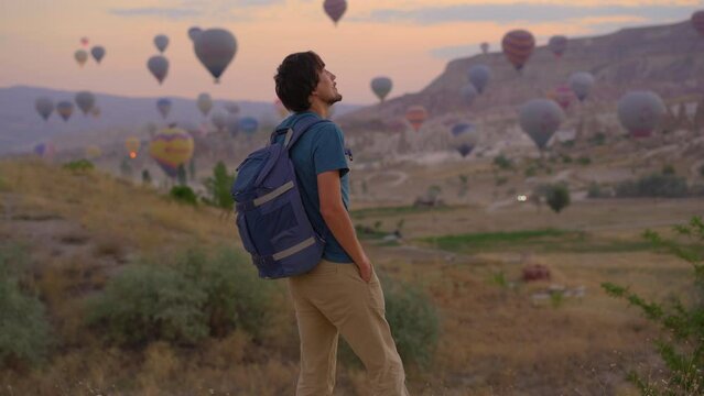 A man tourist is enjoying hot air balloons festival in Cappadocia, Turkey. Happy Travel to Turkie concept.