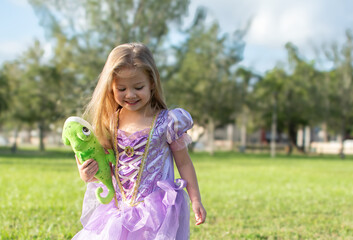 Little blonde girl with long hair cosplaying Rapunzel with a chameleon Pascal. Blonde little girl...