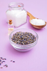 Coarse sea salt in a jar and spoon, lavender essential oil and dried lavender flowers