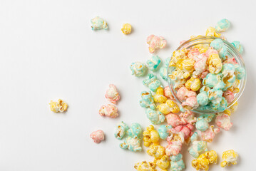 Top view of color sygary popcorn in glass bowl and scattered on a white background isolated - obrazy, fototapety, plakaty