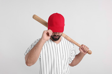Man in stylish red baseball cap holding bat on white background