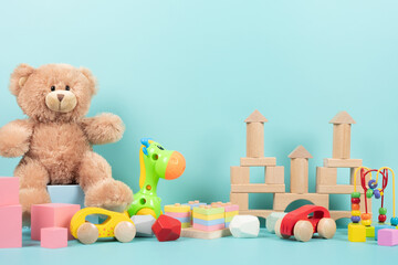 Kids toys collection with teddy bear, wooden blocks for children games. Colorful educational baby toys on light blue background. Front view