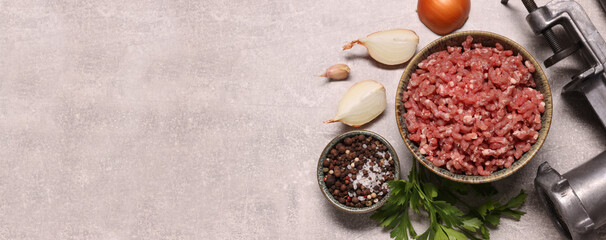 Manual meat grinder, beef mince, peppercorns, onion and parsley on light grey table, flat lay. Banner design with space for text