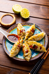 Asian dumplings with hot sauce on the dark wooden background vertical photo