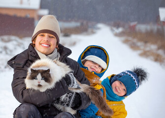 boys plays with a cat outdoors in winter