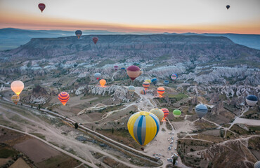 Hot air balloons flying over bizarre rock landscape in Cappadocia. Balloons fly early in the...