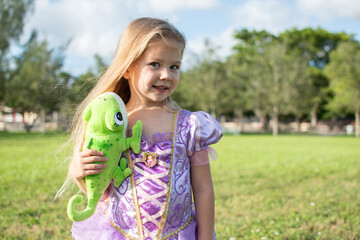 A little blonde girl with long hair cosplaying Rapunzel with a chameleon Pascal. Blonde little girl...