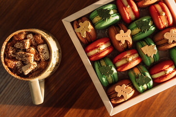 Christmas macarons with chocolate trees and people in a white box with a mug of hot coffee.
