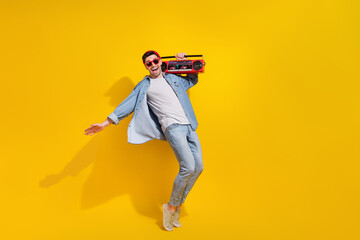 Fototapeta na wymiar Full length photo of cheerful positive guy wear denim jacket dancing enjoying boom box songs isolated yellow color background