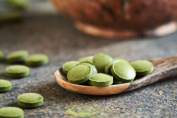 Green barley grass tablets on a spoon on a table
