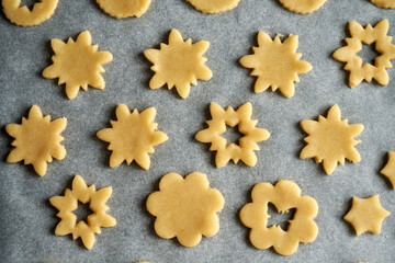 Shapes made of pastry dough on a sheet of baking paper - preparation of Linzer Christmas cookies