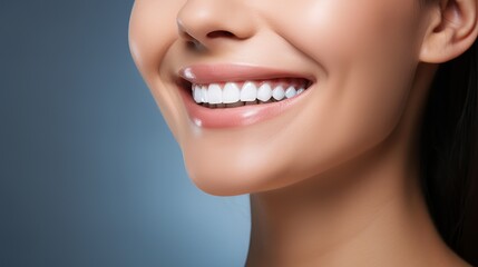 Fototapeta premium Standing on a blue background, a cheerful glamour girl with cute make-up smiling with white teeth and looking happy is captured in a close up portrait.