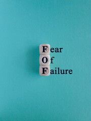 Wooden cubes with words FOF fear of failure. Beautiful blue background. Copy space. Business, fear...