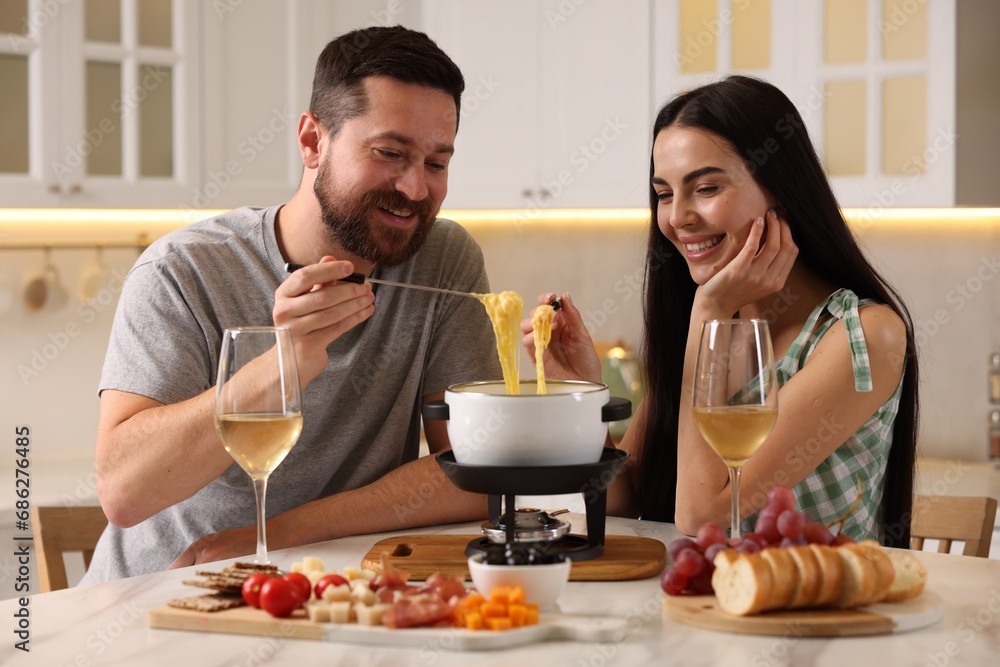 Wall mural affectionate couple enjoying cheese fondue during romantic date in kitchen