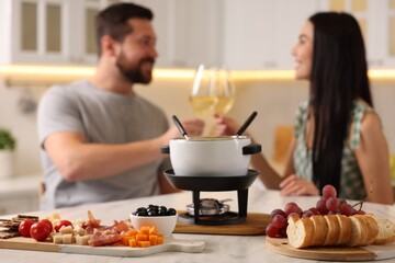 Couple spending time together during romantic date in kitchen, focus on fondue