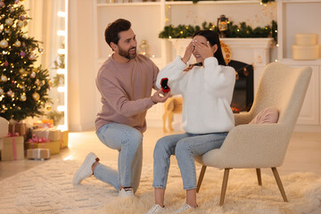 Man with engagement ring making proposal to his girlfriend at home on Christmas