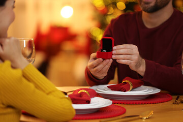 Man with engagement ring making proposal to his girlfriend at home on Christmas, closeup
