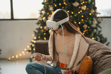 Relaxing in a homey Christmas environment, a trendy young lady sports a virtual reality headset.