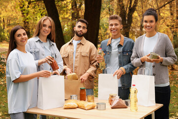 Portrait of volunteers packing food products at table in park