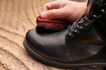 Black leather boots are cleaned with shoe cream. The concept of shoe care.