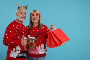Senior couple in Christmas sweaters, reindeer headband and party glasses with shopping bags on...