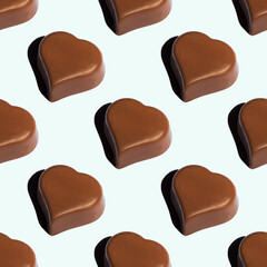 Seamless pattern of heart-shaped chocolates with a shadow on a blue background Favorite food background. A symbol of love